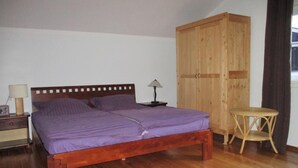 A bedroom with a wooden bed, a nightstand, a lamp, a wardrobe, and a small round table. - Gemütliches Ferienhaus in Lofer mit Garten by Interhome (Lofer)