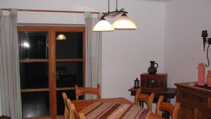 A dining area with a wooden table and chairs, a window with curtains, and a wall-mounted radio. - Gemütliches Ferienhaus in Lofer mit Garten by Interhome (Lofer)