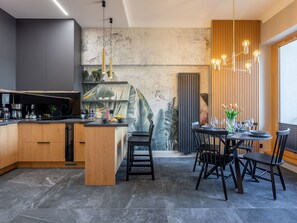 A modern kitchen with a central island, dark tiles, and a dining area with a table set for four. - Tower 26 - Ihr Ferienappartement in Swinemünde by Interhome (Swinoujscie)