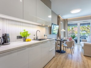 A modern kitchen with a central island, a dining area with a table and chairs, and a view of the outdoors through large windows. - Appartement Jachtowa direkt am Hafen von Usedom by Interhome (Swinoujscie)