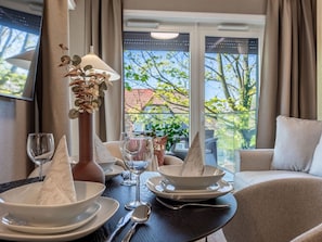 A dining table set with white plates, bowls, a wine glass, and a vase with dried flowers. - Appartement Jachtowa direkt am Hafen von Usedom by Interhome (Swinoujscie)