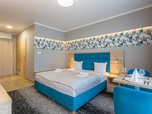 A modern hotel room with a large bed, a wooden headboard, a geometric wall decoration, a small table with a chair, and a desk with a chair. - in einzigartiger Lage auf Usedom by Interhome (Swinoujscie)