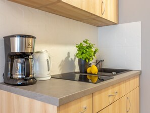 A kitchen with a coffee maker, a kettle, a potted plant, and a lemon on the counter. - in einzigartiger Lage auf Usedom by Interhome (Swinoujscie)
