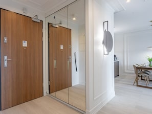A modern hotel room with a wooden wardrobe, a glass partition, and a dining area with a table and chairs. - Ruhige Ferienwohnung am Meer by Interhome (Swinoujscie)