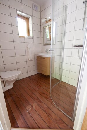 Een badkamer met toilet, wastafel en een douchecabine met glazen wanden.