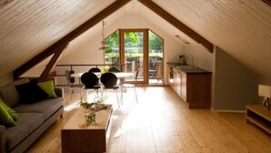 Une chambre mansardée comprenant un coin repas, une cuisine et un canapé avec des coussins.