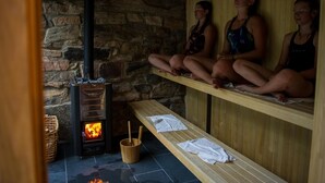 Un sauna aux murs de pierre, doté d’un poêle à bois, de bancs et de serviettes.