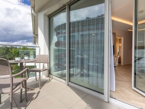 Ein moderner Balkon mit Glastür zu einem Wohnbereich, ausgestattet mit Tisch und Stühlen.