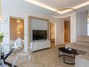 Ein modernes Wohnzimmer mit einem Flachbildfernseher, einem Glastisch und einem Sofa.