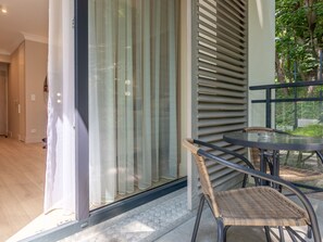 Una habitación moderna con puerta de vidrio, sillas de mimbre y una pequeña mesa redonda.