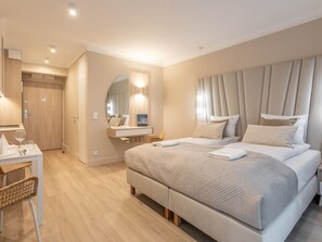 Habitación de hotel moderna con una cama grande, una mesita de noche, un espejo y un escritorio con una silla.