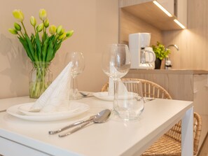 Ein Esstisch ist gedeckt mit Tellern, Besteck und Weingläsern, dazu steht ein Strauß Tulpen.