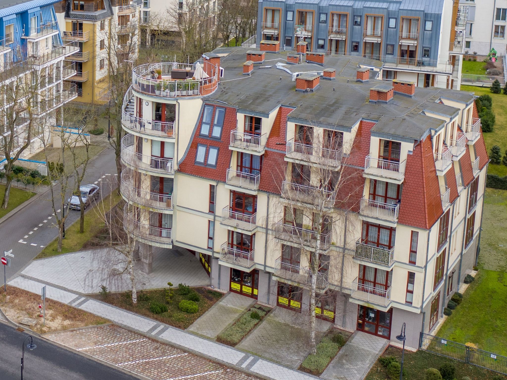 En flereetagers boligbygning med altaner, en central gårdhave og parkeringsplads.