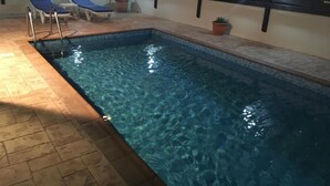 A rectangular indoor pool with clear water, surrounded by a tiled deck. There are lounge chairs and a small ladder leading into the pool. - "Palmenvilla" mit privatem Balkon by Interhome (Agios Georgios Pegeias)