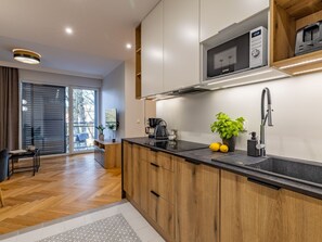 A modern kitchen with wooden cabinets, a black countertop, a microwave, a coffee maker, and a plant. - am Meer, Urlaub auf der Insel Usedom, Apartment Matejki 27 by Interhome (Swinoujscie)