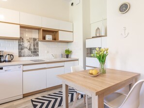 A modern kitchen with white cabinets, a wooden countertop, a coffee maker, and a sink. There is a dining table with chairs and a vase of flowers. - Tower 22 in ruhigem Stadtviertel by Interhome (Swinoujscie)