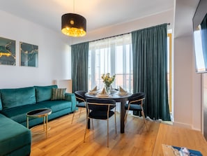 A modern living room with a teal sofa, a round dining table with black chairs, and a pendant light. - Appartement Tower 65 in einem ruhigen Stadtviertel by Interhome (Swinoujscie)