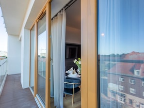 A balcony with a sliding glass door, a small table with a vase of flowers, and a view of buildings in the background. - Appartement Tower 65 in einem ruhigen Stadtviertel by Interhome (Swinoujscie)