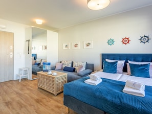 A modern hotel room with a large bed, a sofa, a small table, and a wooden crate. - Ferienappartement Blue Rose direkt am Park by Interhome (Swinoujscie)
