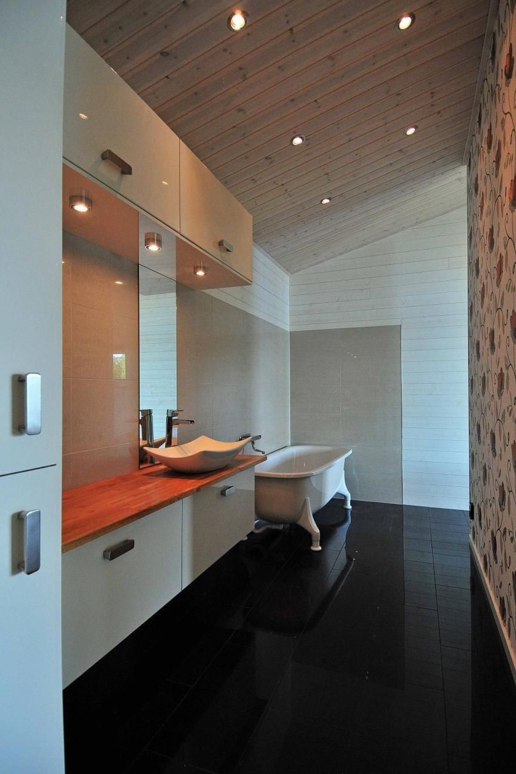 A modern bathroom with a freestanding bathtub, a wooden vanity, and a large mirror.