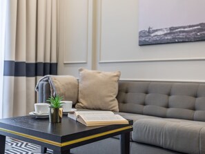 Ein modernes Wohnzimmer mit einem grauen Sofa, einem schwarzen Couchtisch, einem Buch, einer Tasse und einer kleinen Pflanze.