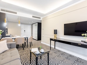 Ein modernes Hotelzimmer mit Essbereich, einer Couch, einem Couchtisch und einem Fernseher.
