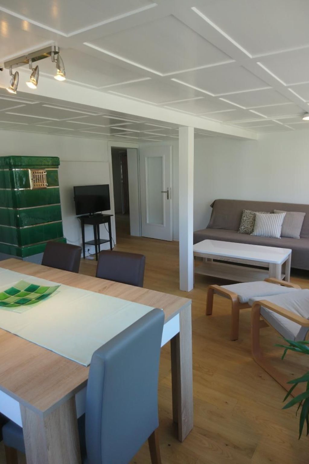 En moderne stue med spiseplads, et grønt skab og et fjernsyn.
