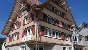 Un edifici de diversos pisos amb façana vermella i blanca, nombroses finestres i un cartell visible de 'Zwingli's'.
