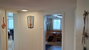 Una habitació àmplia amb terres de fusta, una zona de menjador amb taula i cadires, i una finestra amb cortines.