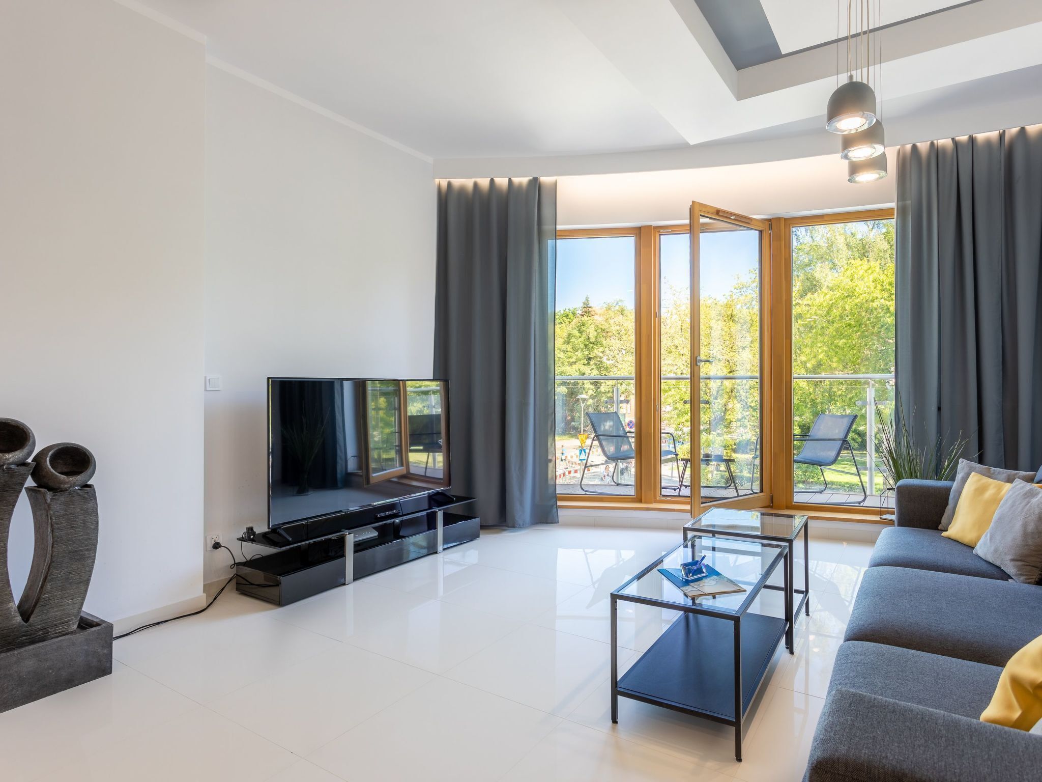 A modern living room with a flat-screen TV, a glass coffee table, and a sofa.
