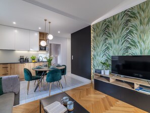 A modern living room with a wooden herringbone floor, a dining area with teal chairs, a flat-screen TV on a wooden stand, and a large plant wall. - am Meer, Urlaub auf der Insel Usedom, Apartment Matejki 16 by Interhome (Swinoujscie)
