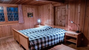 Una habitación de madera con una cama, un escritorio y una mesita de noche.