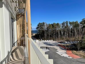 Ein modernes Gebäude mit Holzfassade und Blick auf Strand und Wald.