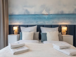 Ein Hotelzimmer mit einem Bett, zwei Nachttischen und einem Segelboot-Bild an der Wand.