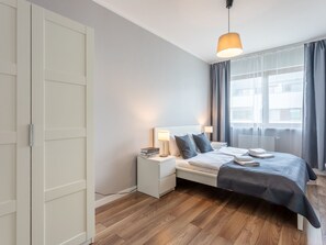 A modern bedroom with a bed, bedside tables, and a hanging light fixture. - Zuza mit schönem Sonnenbalkon by Interhome (Swinoujscie)