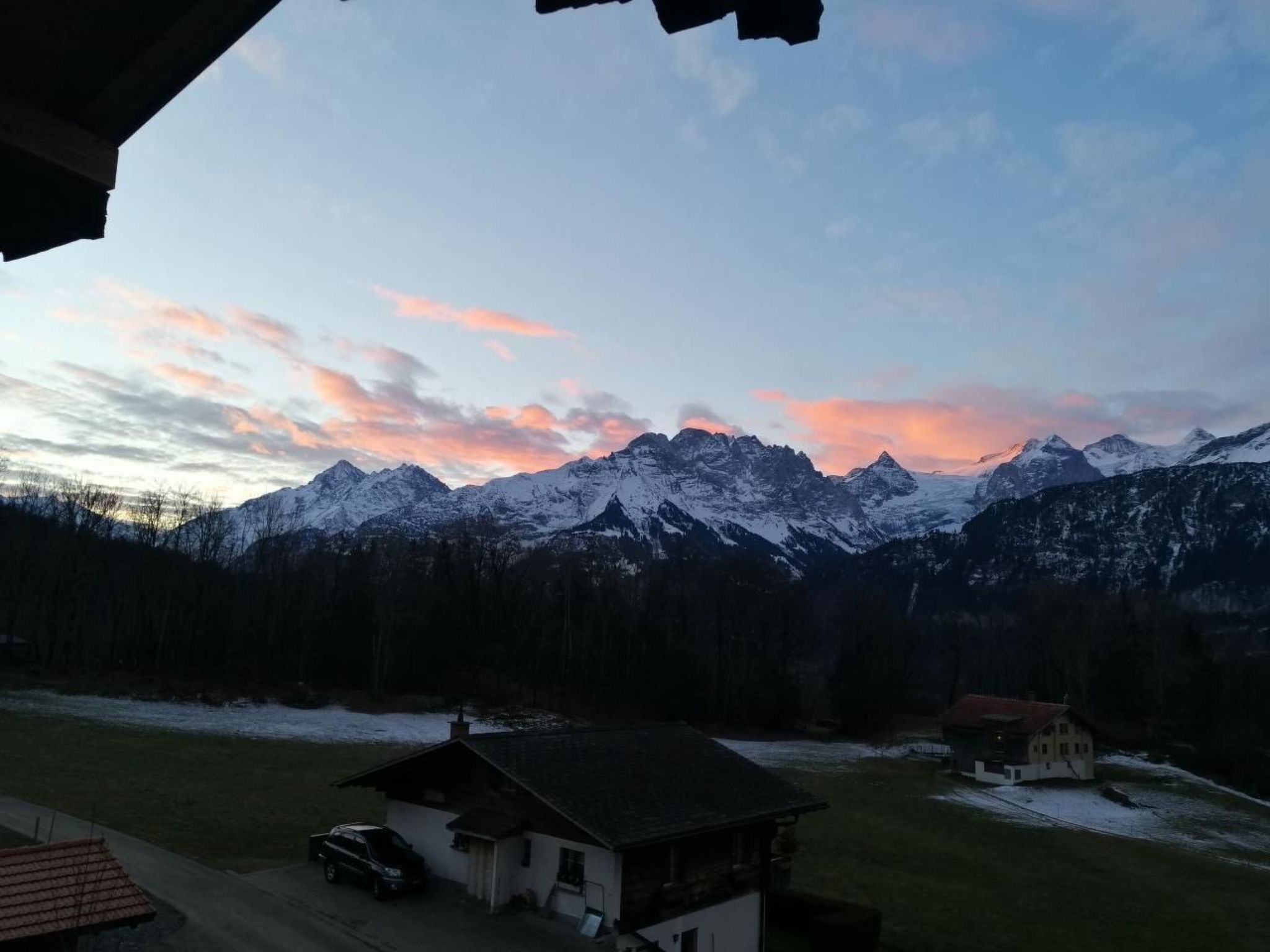 Un paysage de montagne avec des sommets enneigés et un ciel au coucher du soleil.