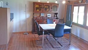 Un coin repas comprenant une table en bois, deux chaises et un buffet orné de panneaux décoratifs.