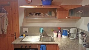 Une cuisine de taille réduite, équipée d’un évier, d’une cuisinière et de divers appareils électroménagers.