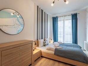 Ein modernes Schlafzimmer mit einem Bett, Nachttischen, einer Holzkommode, einer Karte an der Wand und einem Fenster mit Vorhängen.