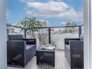 A balcony with wicker furniture, a small table with a cup and book, and a view of buildings and trees. - am Meer, Urlaub auf der Insel Usedom, Apartment 206 by Interhome (Swinoujscie)