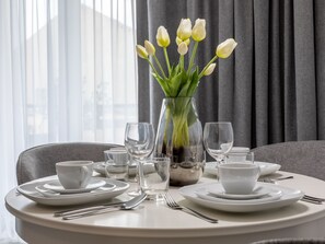 A dining table set with white plates, cups, and cutlery, a vase with white tulips, and a silver teapot. - am Meer, Urlaub auf der Insel Usedom, Apartment 206 by Interhome (Swinoujscie)