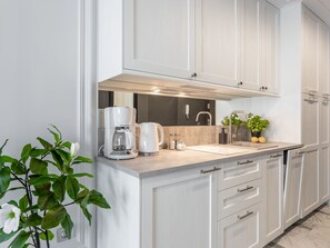 A modern kitchen with white cabinetry, a built-in coffee maker, a sink, and a potted plant. - am Meer, Urlaub auf der Insel Usedom, Apartment 206 by Interhome (Swinoujscie)