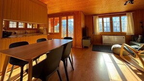 Interior de una cabaña de madera con comedor, cocina y zona de estar.