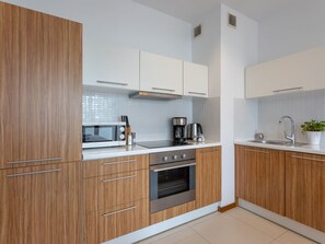 Eine moderne Küche mit Holzausstattung, einer Mikrowelle, einer Kaffeemaschine und einem Spülbecken.