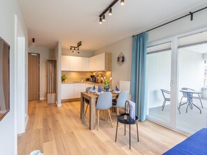 A modern kitchen with white cabinets, a dining area with a table and chairs, and a balcony with a table and chairs. - Urlaub auf Usedom, Apartment Sun Towers A49 by Interhome (Swinoujscie)