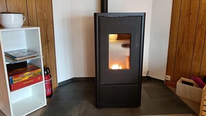 Et moderne værelse med en sort brændeovn, en hvid reol med bøger og en brandslukker.