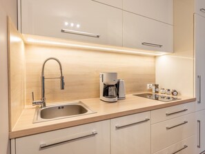 Eine moderne Küche mit integriertem Spülbecken, einer Kaffeemaschine und einer Reihe von Gewürzbehältern auf der Arbeitsfläche.