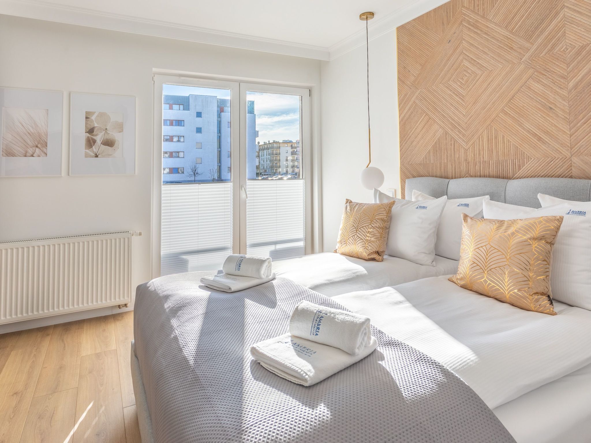 A modern hotel room with a large bed, a view of the city through floor-to-ceiling windows, and a wooden accent wall.