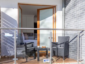 A balcony with wicker furniture, a glass door, and a tiled floor. - Premium-Ferienwohnung Golden Suite in Swinemünde by Interhome (Swinoujscie)