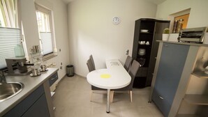 A compact kitchen with a dining table, a coffee machine, and a clock on the wall. - mit Terrasse by Interhome (Opatija/Rukavac)